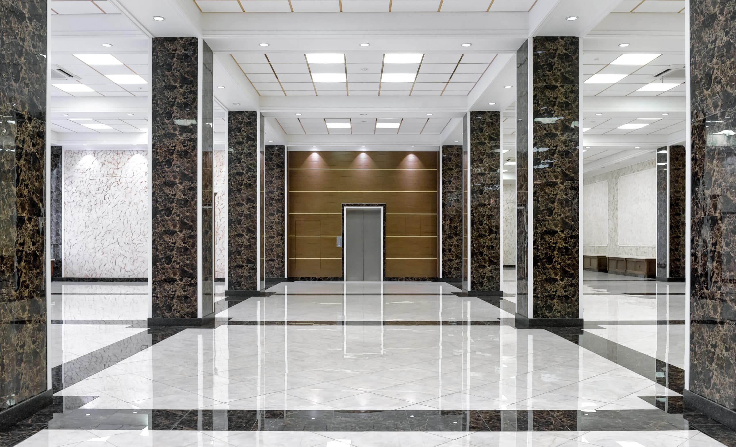 Marble interior of a luxury lobby of company or hotel. Clean corporate hallway with real floor tile. Shiny floor with reflections after professional cleaning. Service of modern office interior