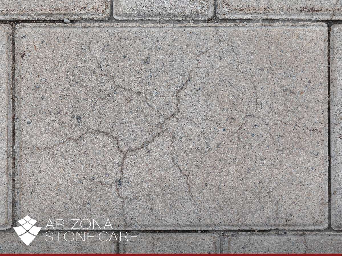 Detailed view of cracked flagstone tile with Arizona Stone Care branding at the bottom