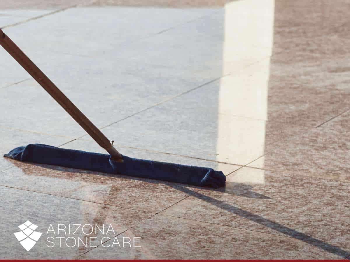 Person mopping a shiny stone surface, demonstrating proper Granite Floor Cleaning techniques